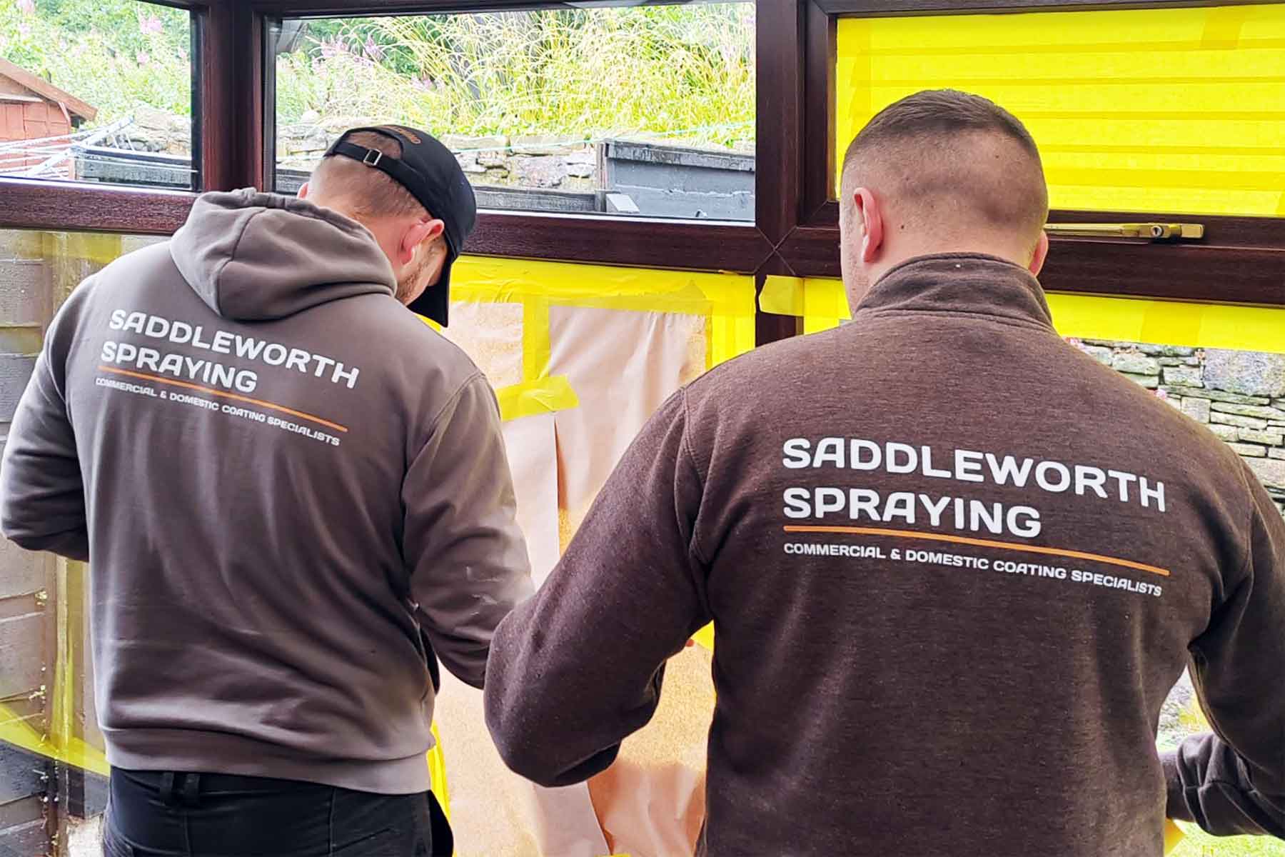 Saddleworth spraying technicians masking up windows ready to spray the frames